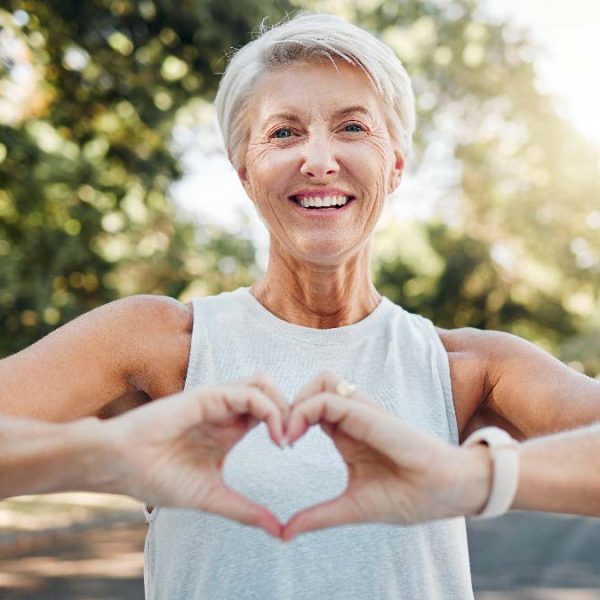 Donna sorridente che fa il gesto del cuore con le mani